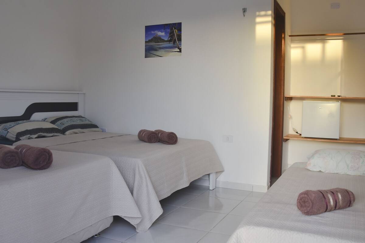 A hotel room with two beds, a small bedside table, a wall-mounted picture, and a sliding door leading to a bathroom.