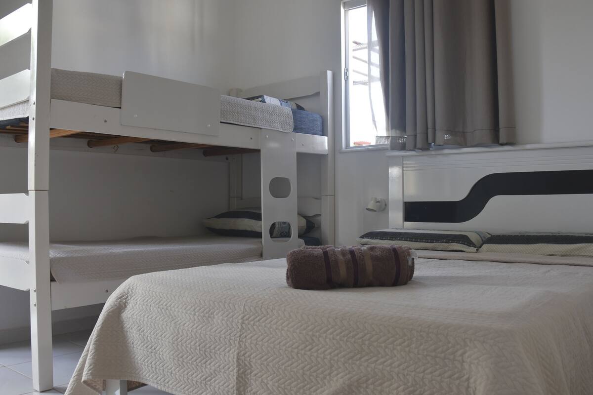 A bunk bed room with a white bedspread and a brown pillow.