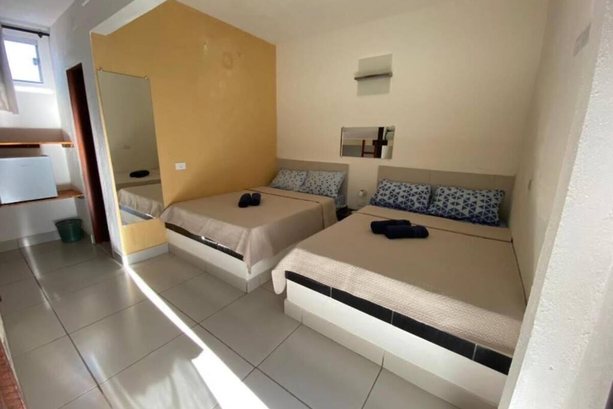 A room with two beds, a small window, and a mirror on the wall.
