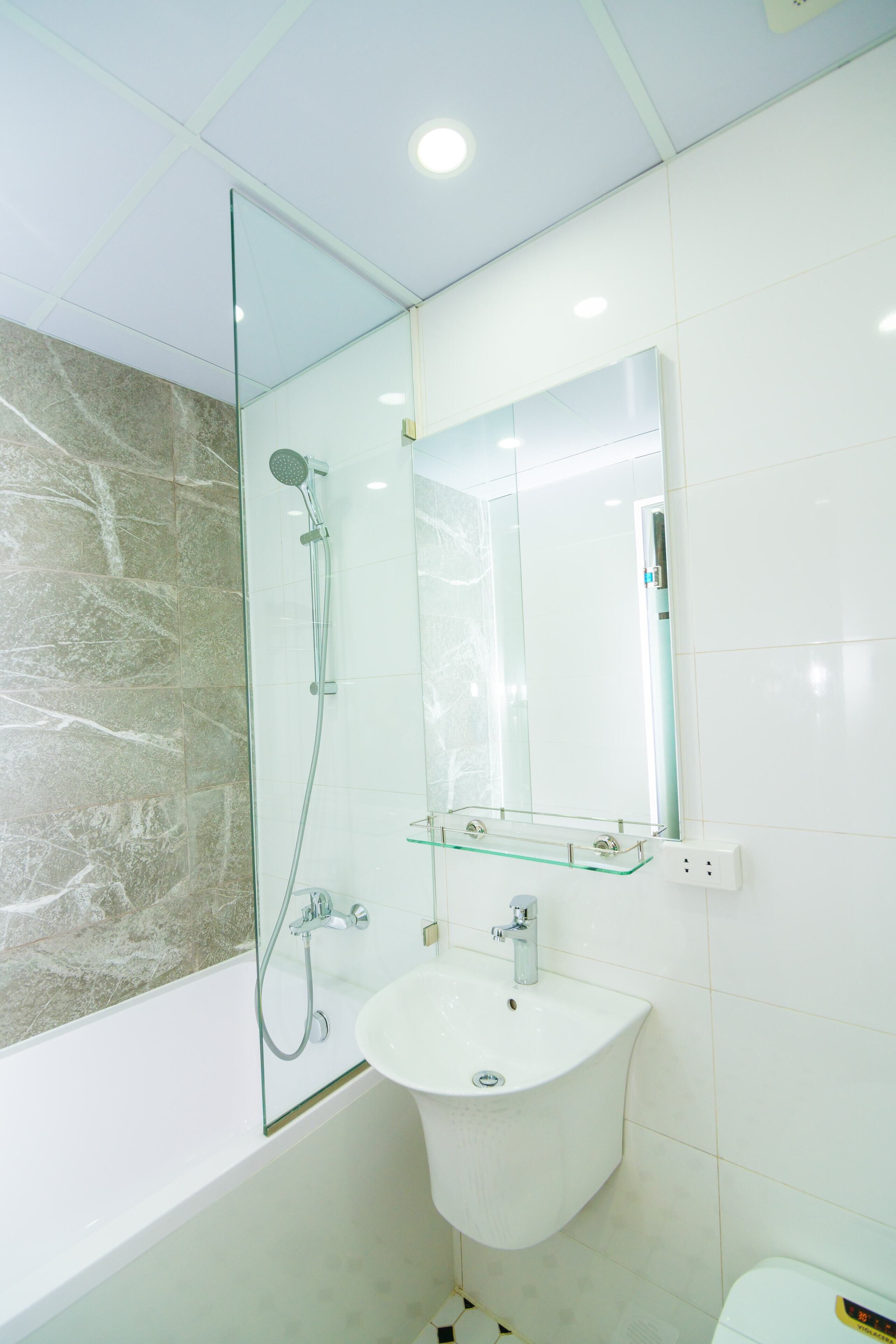 Une salle de bain moderne avec une douche à parois de verre, un lavabo blanc et un grand miroir au-dessus.