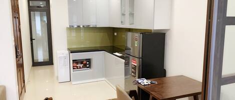 A compact kitchen with white cabinets, a built-in oven, and a refrigerator.