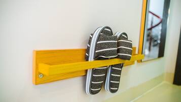 A pair of striped slippers hanging on a yellow rack against a wall.