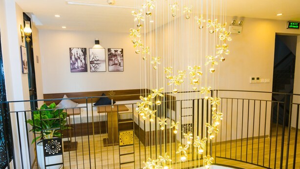 Ein mehrgeschossiges Interieur mit einer zentral hängenden Leuchte, einer Sitzecke und einer Treppe.