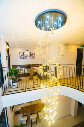 A multi-level interior with a central hanging light fixture, a seating area, and a staircase.