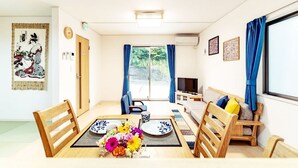 Ein modernes Wohnzimmer mit Esstisch, Stühlen, einer Couch und einem Fernseher.