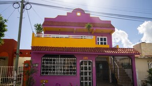 A two-story building with a purple and yellow facade, a large window, and a gate. - Casa Zac Nicte Mx ROOM IXCHEL (CANCUN)