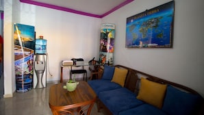A living room with a sofa, a coffee table, a water dispenser, and a map on the wall. - Casa Zac Nicte Mx ROOM IXCHEL (CANCUN)
