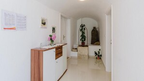 Ein Flur mit einem Holztisch, einer Topfpflanze und einem kleinen Regal mit einer Vase.