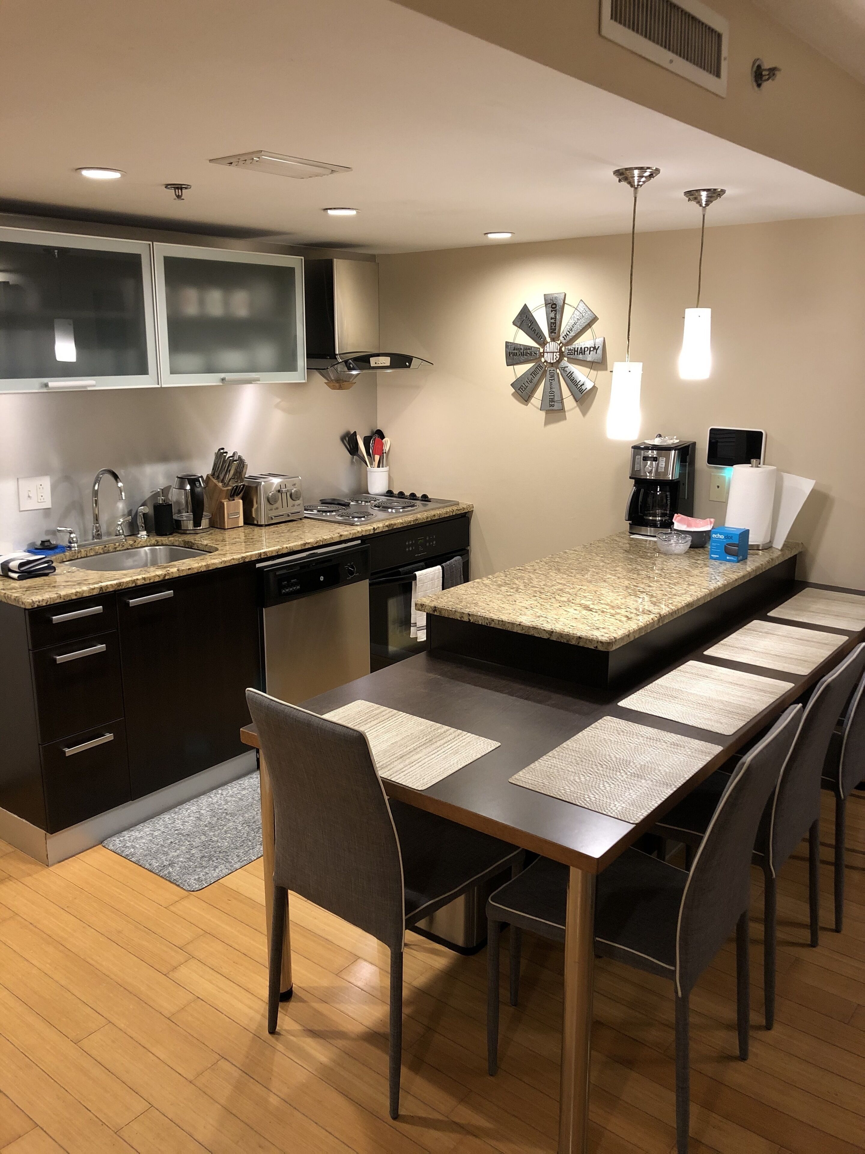 Een moderne keuken met een centraal eiland, donkere kasten en een eetgedeelte met een lange tafel en stoelen.