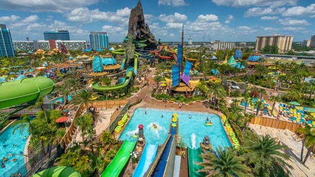 Un parc aquatique doté de nombreux toboggans et de plusieurs piscines, entouré de palmiers et de bâtiments.