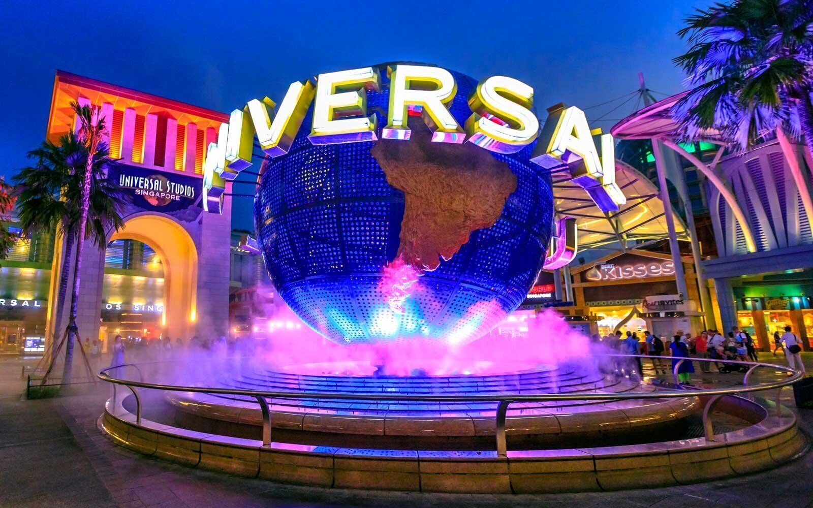 Un globo iluminado de gran tamaño con la palabra 'UNIVERSAL' frente a un centro comercial.