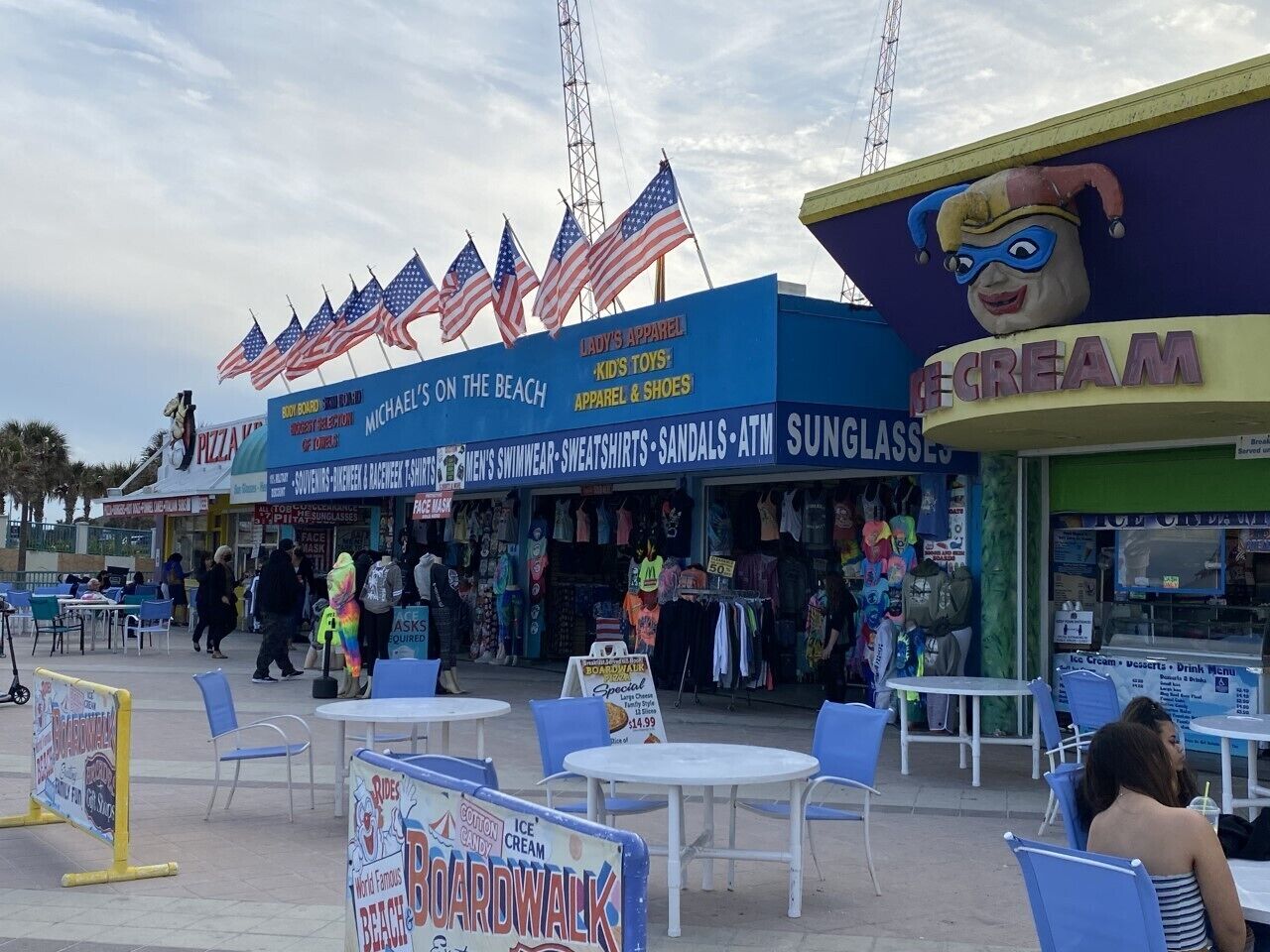 Een promenade langs het strand met winkels, waaronder een kledingzaak en een ijssalon.