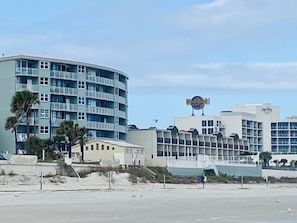 A beachfront hotel with a curved building, multiple balconies, and a prominent sign.
