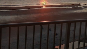 A sunset over the ocean with a beach in the foreground.