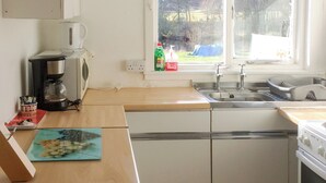 Eine Küche mit einer Kaffeemaschine, einem Spülbecken und einem Fenster mit Blick auf Bäume und Hügel.