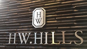A sign with the letters "HW" in a hexagon above the name "HW HILLS". - JR Komagome Apartment 1-1 (Tokyo)