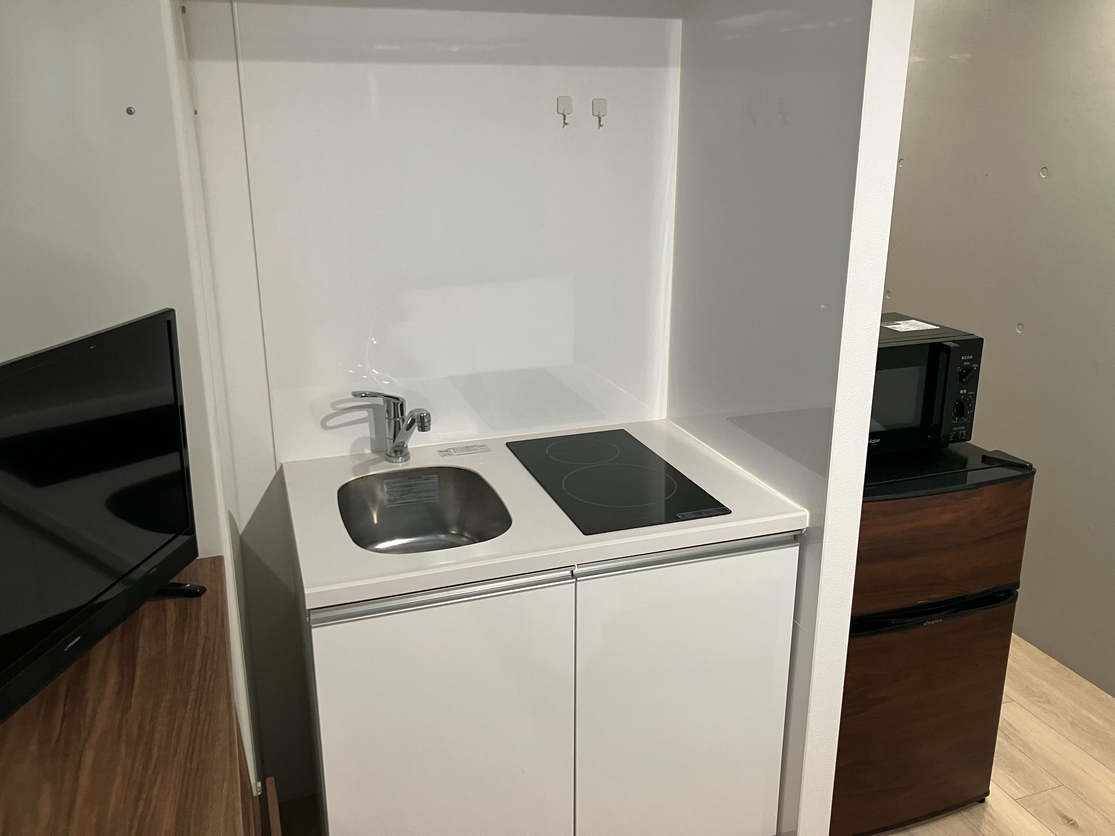 A compact kitchenette with a sink, a microwave, and a small refrigerator. - JR Komagome Apartment 1-1 (Tokyo)
