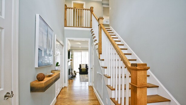 A hallway with a wooden staircase, a mounted artwork, and a shelf with decorative items. - 5 Bedroom renovated Home in Great Waters at Reynolds Lake Oconee (Eatonton)