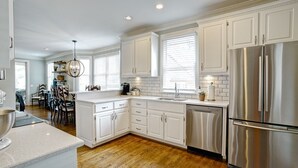 A modern kitchen with white cabinetry, a stainless steel refrigerator, and a wooden floor. - 5 Bedroom renovated Home in Great Waters at Reynolds Lake Oconee (Eatonton)