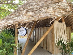 A covered walkway with a sign indicating showers and camp toilets. - Beach House Camp (Sattahip)