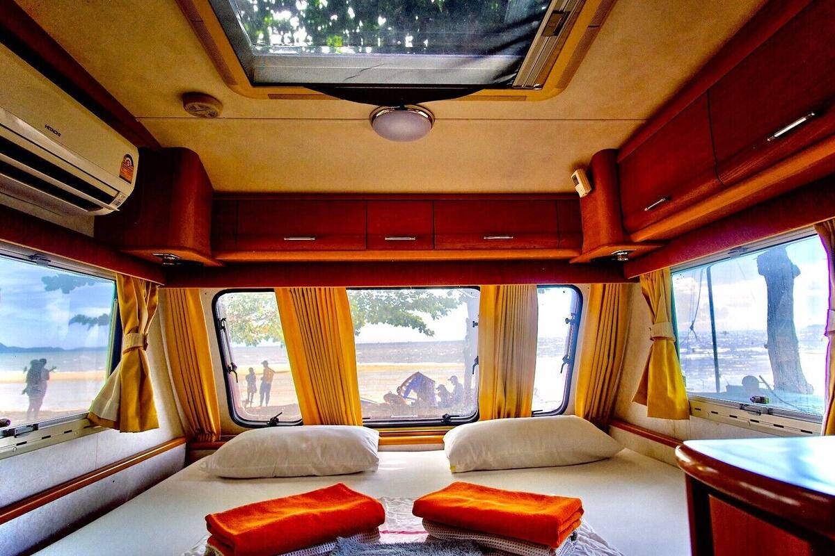 A cozy interior with a bed, curtains, and a view of the beach.