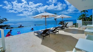 A pool area with lounge chairs and umbrellas, overlooking a clear blue sky and ocean view. - The Most Beautiful place (Samana City)
