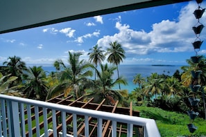 A balcony with a view of the ocean and palm trees.