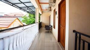 A corridor with a tiled floor, a wooden door, and a window on the right. - SPOT ON 2875 Kost Pandawa Syariah (Cilacap)
