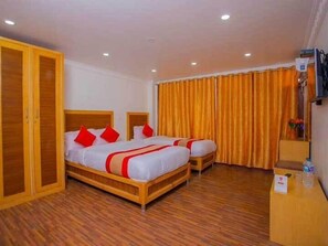 A hotel room with two beds, wooden flooring, and a large wardrobe.