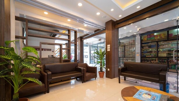 A modern lobby with two sofas, a wooden table, and potted plants. - Hotel Pancha Buddha (Kathmandu)