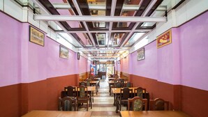 A restaurant with a long counter and multiple tables, featuring a high ceiling with exposed beams and a tiled floor. - Hotel Pancha Buddha (Kathmandu)