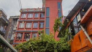 A multi-story building with a red facade and blue accents, featuring balconies and windows. - Hotel Pancha Buddha (Kathmandu)