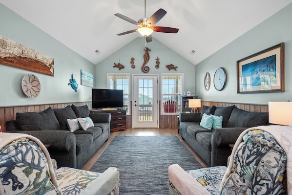 A living room with two sofas, a television, and a ceiling fan.