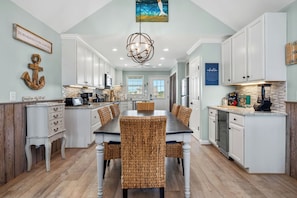 A kitchen with white cabinets, a dining table with wicker chairs, and a chandelier.