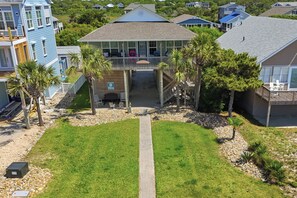 A two-story building with a covered porch, a paved walkway, and a small lawn area.