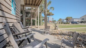 Una edificación de madera con un patio cubierto, mobiliario exterior y un letrero que indica que es una propiedad de alquiler.