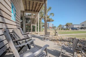A wooden building with a covered patio area, outdoor seating, and a sign indicating a rental property.