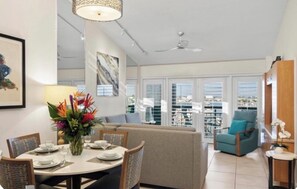 A dining area with a round table set for four, a sofa, and a chair.