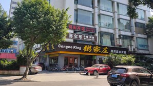 A building with multiple signs, including one for a restaurant named "Congee King" and another for a hotel. - Foshan school age Youth Hostel (Foshan)