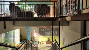 A multi-level interior with metal railings, ceiling fans, and potted plants. - Foshan school age Youth Hostel (Foshan)