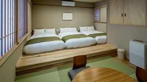 Una habitación con tres camas dispuestas contra una pared, una mesita y un radiador.