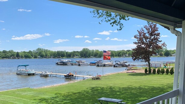 Vista sul lago da un portico coperto, con tavolo da picnic e una bandiera.