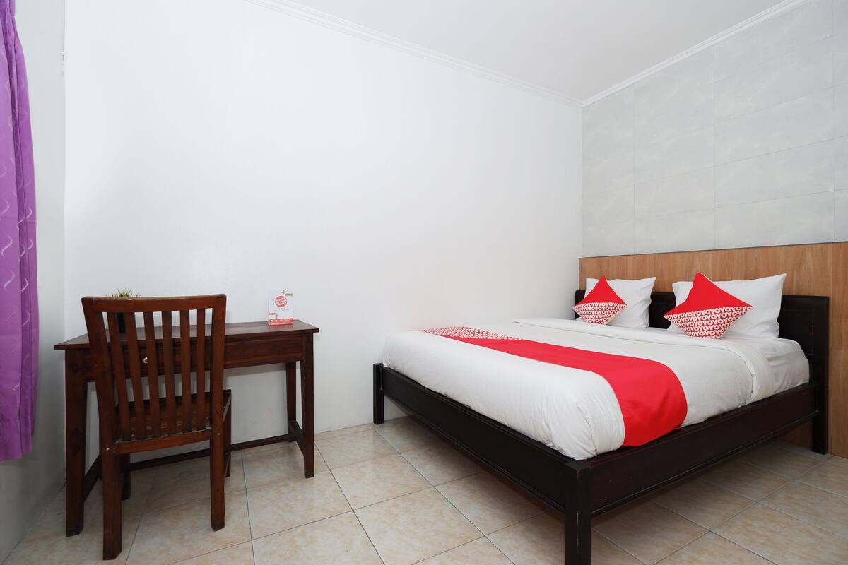 A bedroom with a bed, a wooden chair, and a small table.