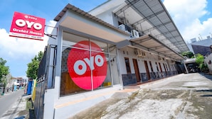 Un bâtiment moderne avec une grande enseigne « OYO Orchid House », de grandes fenêtres et un espace extérieur couvert.