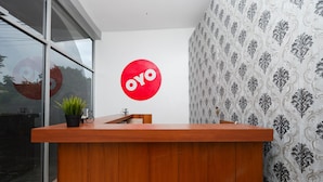 Un comptoir d’accueil avec un revêtement en bois, une plante en pot et un grand logo rouge circulaire sur le mur.