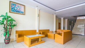 Zona de recepción con un sofá, una mesa y una planta en maceta.