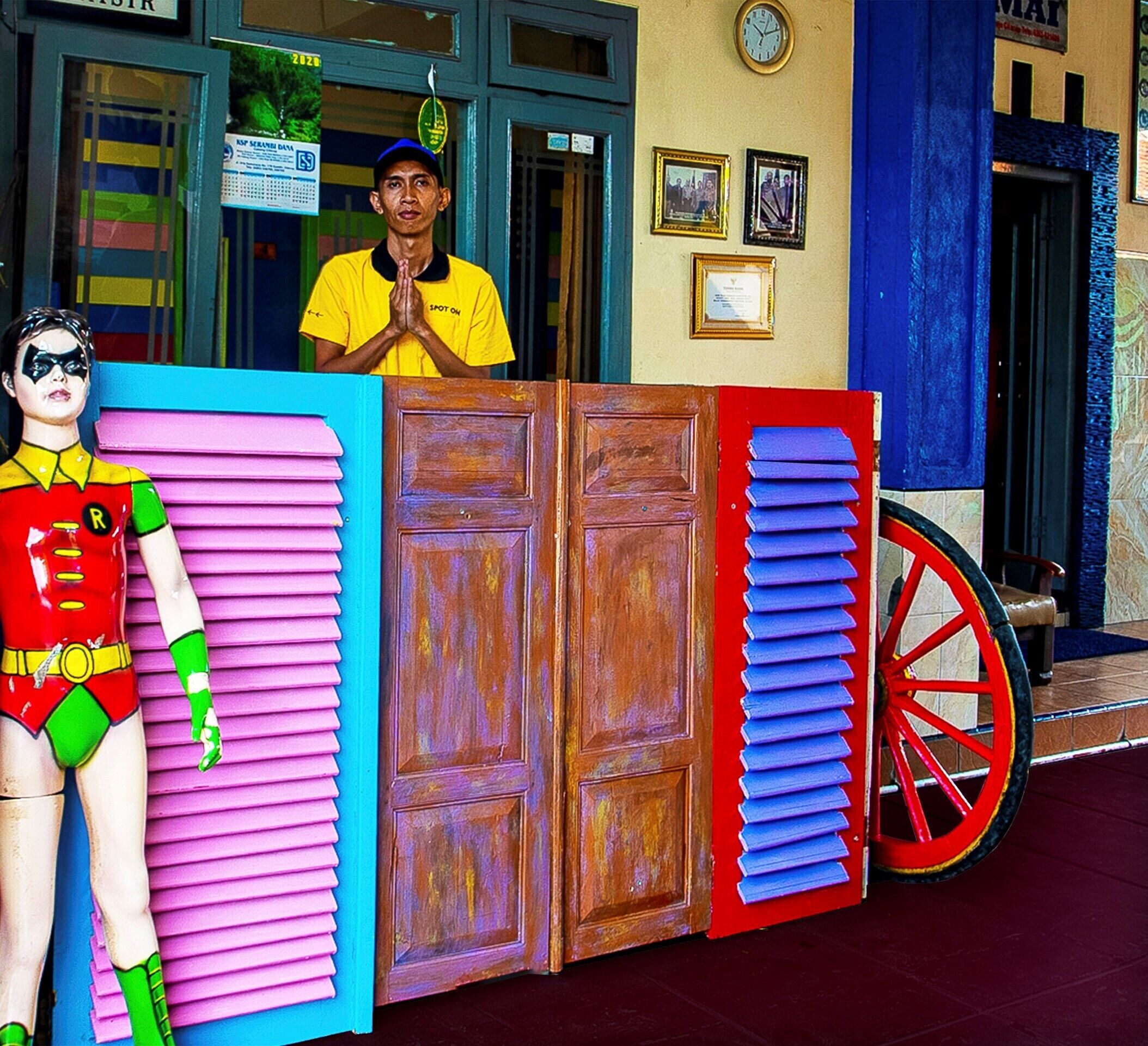 A storefront with a large display of colorful doors and a mannequin dressed as a superhero.