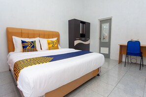 A hotel room with a bed, a wardrobe, a desk, and a chair. - SPOT ON 2830 Azka Guest House Syariah (Cilacap)