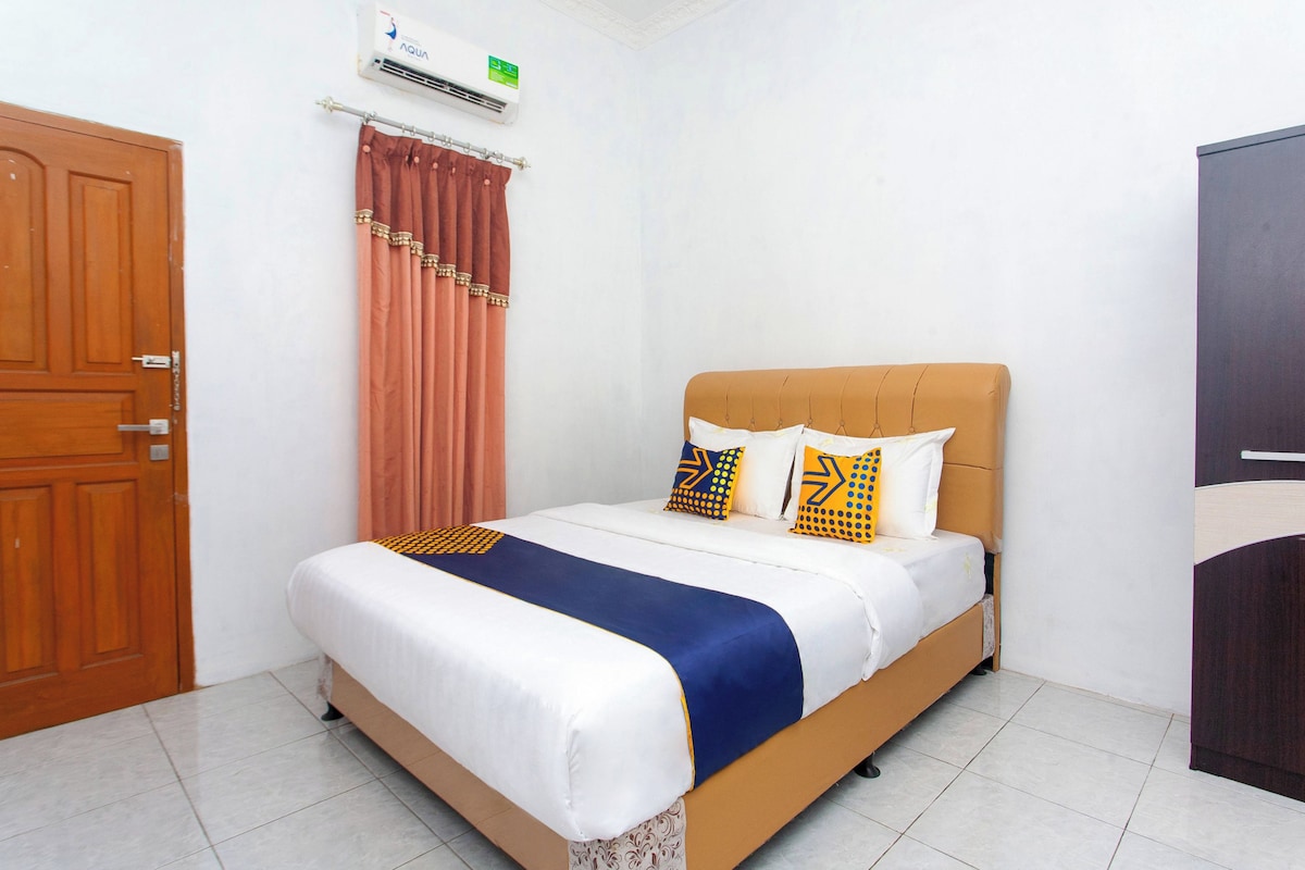 A bedroom with a bed, curtains, an air conditioning unit, and a wardrobe.