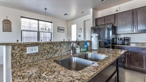 A kitchen with granite countertops, stainless steel sink, and dark wooden cabinets. - Lovely New Home in the North Woods (Flagstaff)